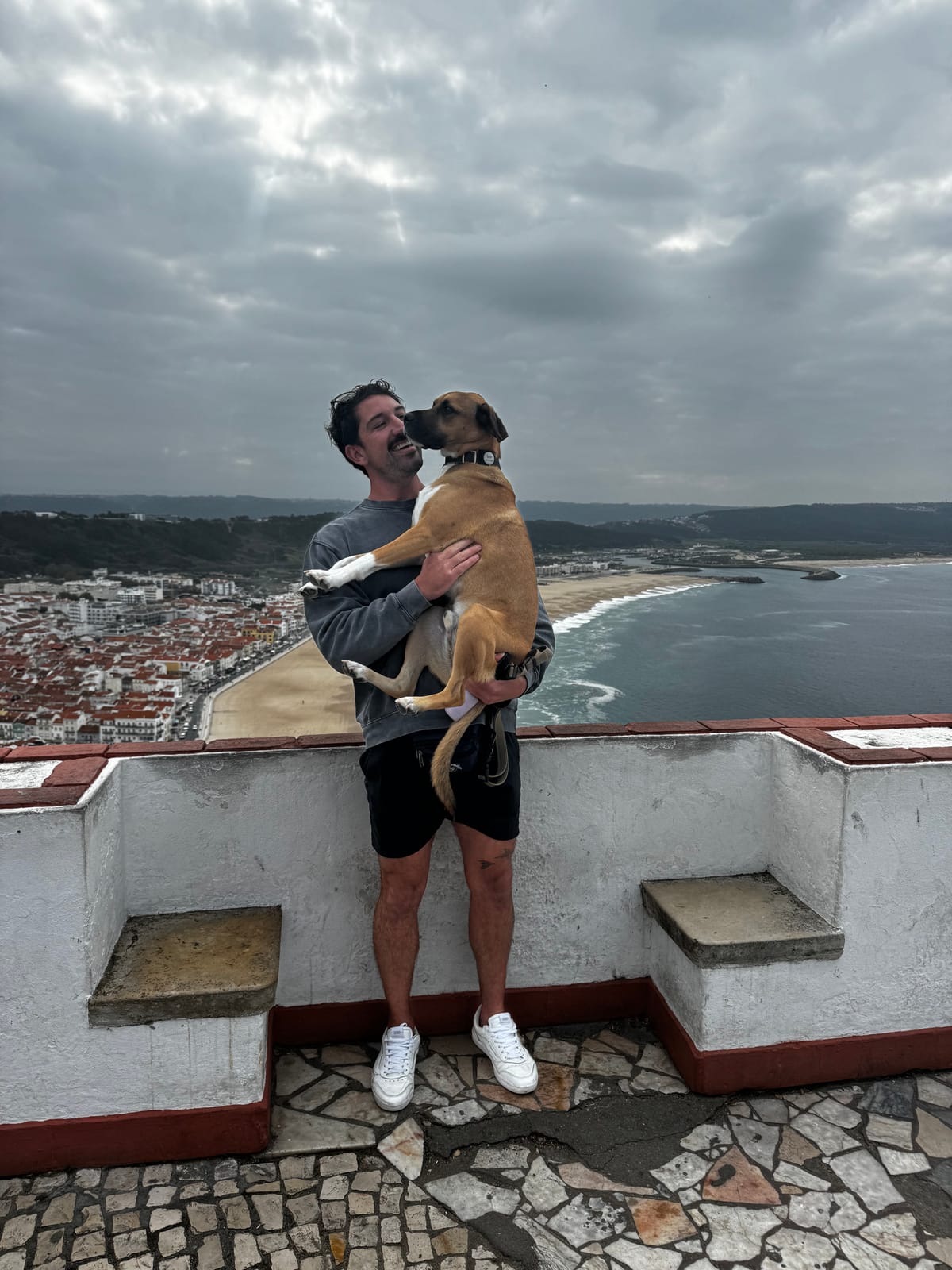 Danny holding Copper above the beach at Nazaré, Portugal